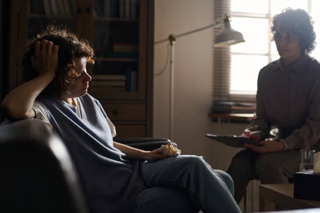 Young woman sitting on a sofa in a therapy room receiving compassionate support